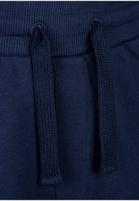 Navy blue sweatpants featuring a ribbed waistband, adjustable drawstrings, and a soft texture. Close-up view highlighting the weave of the drawstring.