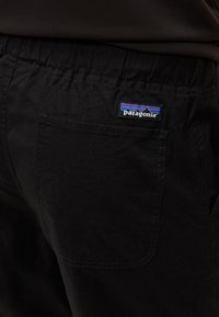 Μαύρο παντελόνι με ελαστική μέση και πίσω τσέπη που φέρει μικρό λογότυπο της Patagonia με σχέδιο βουνού.