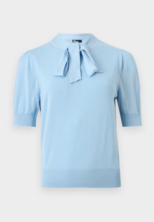 Haut tricoté bleu clair à manches courtes avec poignets et ourlet côtelés, présentant un détail de nœud noué au col rond.