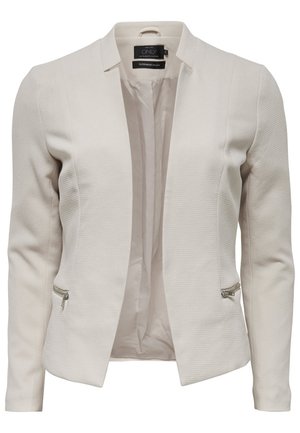 Blazer beige cintré pour femme avec manches longues, devant ouvert, tissu texturé et poches zippées des deux côtés.