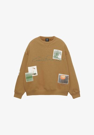 Brązowa bluza z grafikiem z różnymi wzorami. Ma okrągły dekolt, długie rękawy i widoczne detale w przeszyciach.