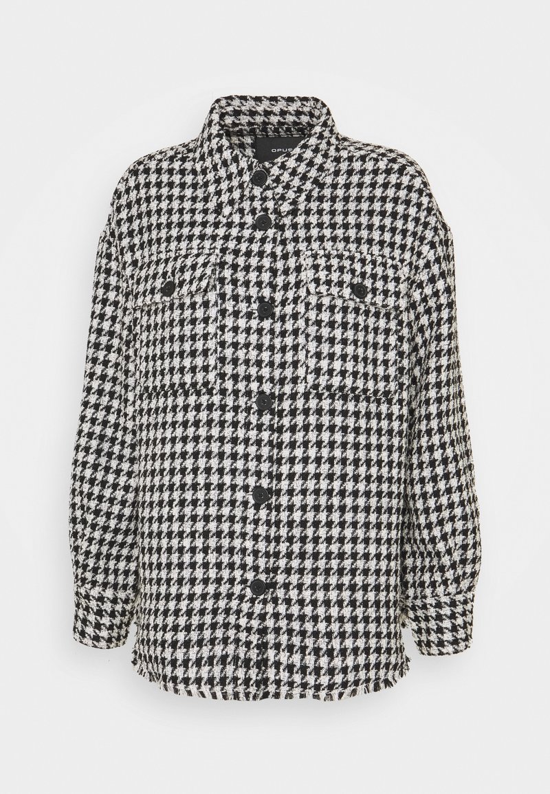 Mustavalkoinen houndstooth-kuvioinen paita-takki, jossa on napitettava etuosa, kaksi rintataskua ja terävä kaulus. Pehmeä, tekstitetty kangas.