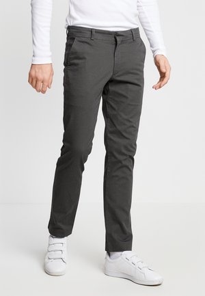 Donkergrijze chinos met een slim fit, met een rechte voorkant, zijzakken en riemlussen, gecombineerd met witte sneakers. Soepele stoftextuur.