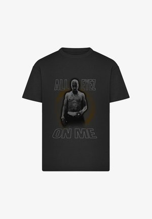 Zwart T-shirt met een man zonder shirt met tatoeages en een ketting, met de tekst "ALL EYEZ ON ME" boven en onder de figuur.