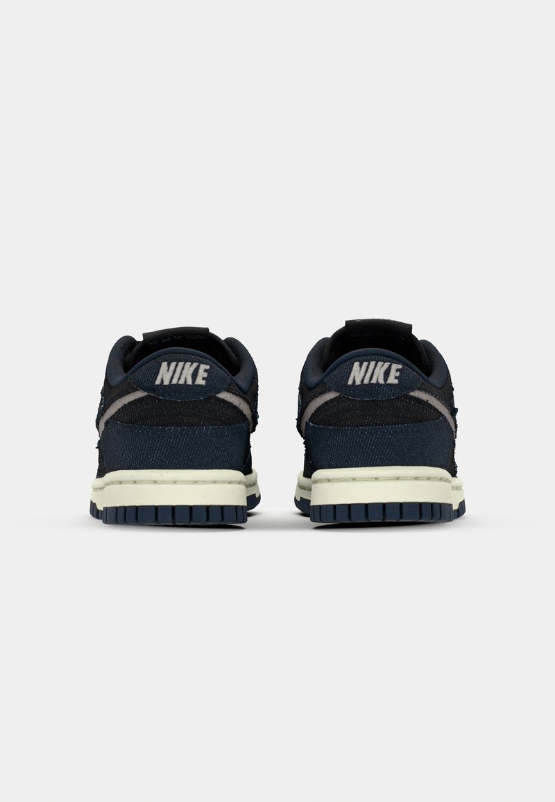 Baskets Nike avec un dessus en textile bleu marine, une semelle intermédiaire crème et une semelle extérieure en caoutchouc bleu foncé. Comprend un col rembourré et des détails de logo.