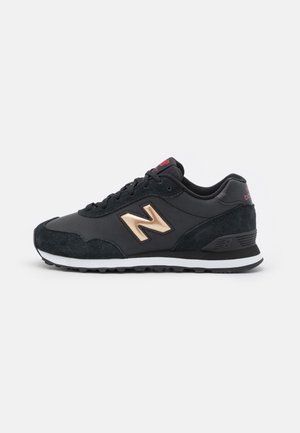 Czarny sneaker New Balance ze złotym logo "N", czarne akcenty zamszowe, biała środkowa podeszwa i teksturowana czarna podeszwa zewnętrzna, widok z boku.