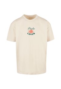Beige katoenen t-shirt met een ronde hals en korte mouwen, met de tekst "Pasta Lover" en een pastatekening in oranje en groen.
