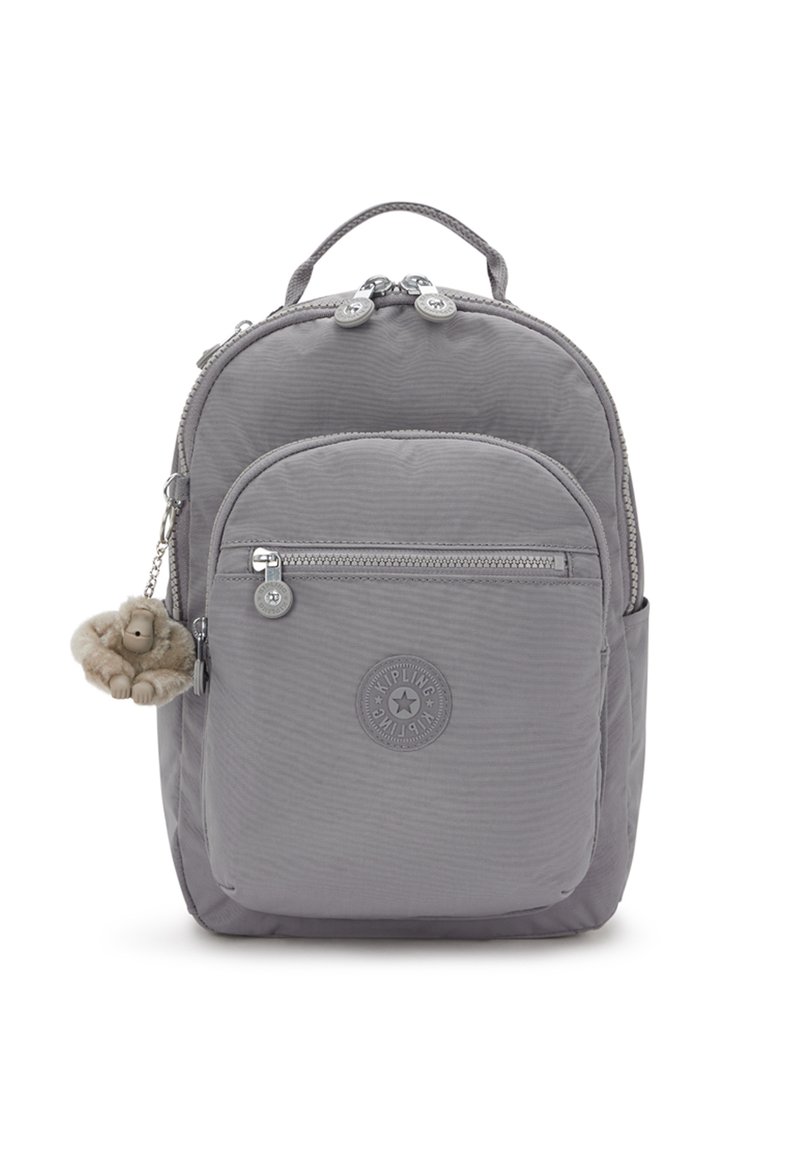 Sac à dos en nylon gris avec une texture lisse, comprenant deux compartiments zippés, un patch logo et un porte-clés en forme de singe.