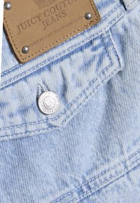 Ανοιχτό μπλε τζιν με δερμάτινο σουέντ ταμπελάκι με την επιγραφή "Juicy Couture Jeans" και ασημί κουμπιά, με ραφές στον ίδιο χρωματισμό.