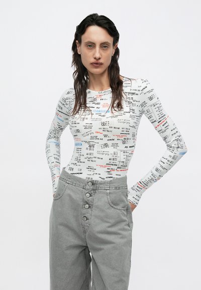 Hosszú ujjú fehér felső vegyes szövegnyomattal. Szürke, magas derekú nadrág öt gombbal és oldalzsebekkel. Simogató tapintású, testhezálló szabás.