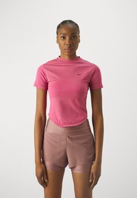Haut de sport rose à manches courtes avec un motif texturé à l'avant, associé à un short de course rose clair et des accents du logo Nike.