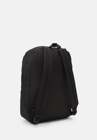 Mochila preta com estrutura acolchoada, alças ajustáveis e uma alça superior para transportar. Feita de tecido durável, com uma textura suave.