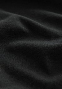 Tessuto nero con una texture liscia, caratterizzato da una leggera elasticità e una superficie leggermente riflettente, con pieghe e increspature delicate.