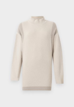Lyse beige sweater med ribbet tekstur, høj hals og lange ærmer. Har en afslappet pasform og subtile farvevariationer.
