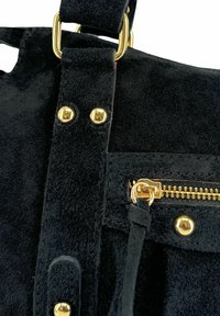 Sac à main en daim noir avec quincaillerie dorée, surface texturée et poche zippée avec tirette, mettant en valeur une sangle détaillée avec des rivets.