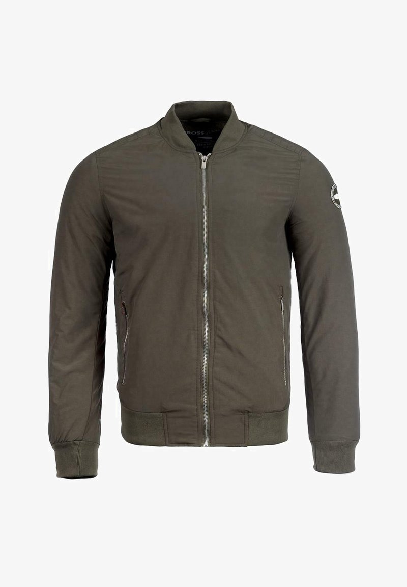 Bomberka w oliwkowej zieleni z zamkiem z przodu, ściągaczami na mankietach i u dołu, płaskim kołnierzem oraz kieszeniami po bokach. Posiada okrągłą naszywkę na rękawie.