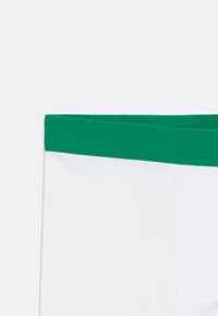 Witte boxershorts met een groene elastische tailleband. Beschikt over een soepele textuur en een eenvoudig ontwerp, waarbij functionaliteit centraal staat.