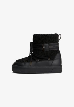 Black ankle boot with fleece upper, laces wrapping around, thick sole, and pull tab at the back.