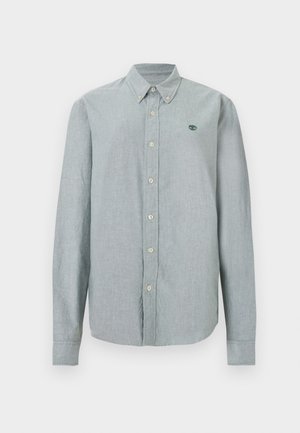 Camicia grigia chiaro a maniche lunghe con bottoni e colletto, con piccolo logo verde sul petto a sinistra, mostrata su uno sfondo semplice.