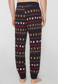 Pantalones de pijama negros con un patrón festivo en rojo, blanco y dorado, con motivos de Papá Noel, hombres de jengibre y renos. Tejido suave, cinturilla elástica.