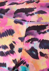 Leggings colorés avec un mélange de motifs abstraits en rose, orange et violet. Caractérisés par un tissu doux, une coupe ajustée et une couture contrastante.