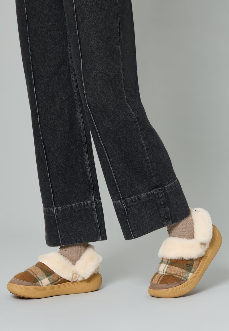 Pantofole slip-on a righe con colletto in pelliccia sintetica, colori marrone e beige, suola in gomma e dettagli beige. Indossate con pantaloni larghi scuri.