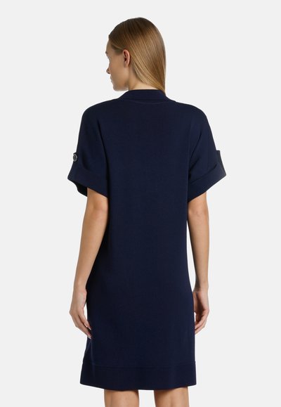 Abito lavorato a maglia blu navy con maniche corte arrotolate e forma dritta. Presenta una texture liscia e dettagli di design discreti sulle maniche.