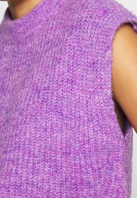 Purple knitted sleeveless sweater with a crew neckline. Soft texture and subtle color variations create a light, cozy appearance.