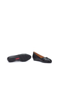 Ballerines en cuir noir avec un petit talon compensé, présentant un design matelassé sur le bout et une semelle texturée avec un accent rouge.