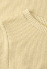 Pull en tricot côtelé couleur crème avec encolure ronde et texture fine verticale visible sur la surface du tissu.