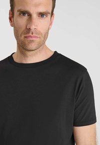 Maglietta nera a maniche corte con scollatura rotonda, realizzata in tessuto liscio, aderente al corpo, con un design semplice e senza fantasie.