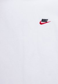 White fabric with a small embroidered black "NIKE" logo and red swoosh on the upper right side.