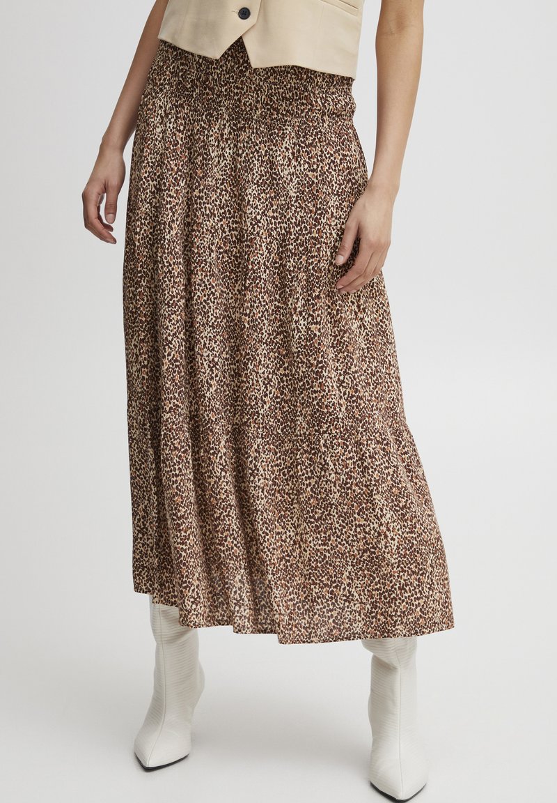 Bruine dierenprint maxi rok met een smocked taille, vloeiende stof en een gelaagd ontwerp. Gepaard met witte, puntige laarzen.
