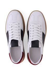 Witte leren sneakers met zwarte en rode accenten, witte veters, rubberen zool en een getextureerde tong met merklogo details.