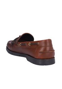 Mocasines de cuero marrón con punta redonda, suela plana de goma negra, costura decorativa y cordones de cuero pasados por ojales dorados.