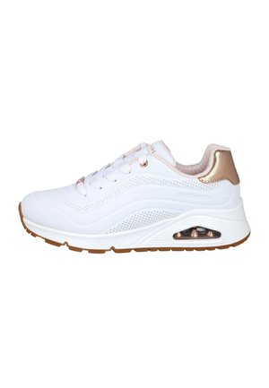 Zapatilla deportiva blanca con lados perforados, cordones blancos, suela acolchada con unidad de aire visible y detalle metálico dorado en el talón.