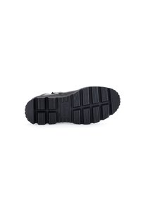 Black shoe sole with textured rubber for traction; prominent horizontal and vertical grooves; embossed brand logo visible.
