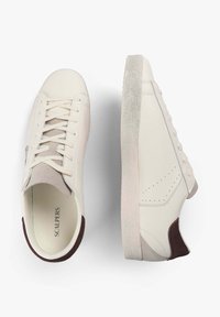 Zapatillas de cuero blancas con una suela texturizada de color gris claro, con acentos beige y un parche en el talón de color marrón oscuro, líneas limpias y cierre de cordones.