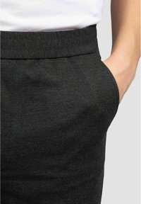Mörkgrå byxor med ett slätt, texturerat tyg, som har en sidoficka och en ren midja. Minimalistisk design, inga synliga mönster.