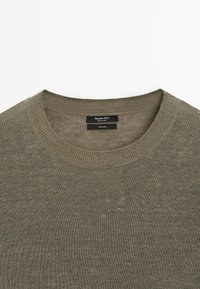 Olivinvihreä pellavainen neulepusero pyöreällä pääntiellä. Siinä on teksturoitu neulospinta ja brändilogo kauluksen sisäpuolella.