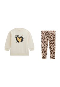 Creme sweatshirt med sort og gul hjertegrafik samt teksten "Guess Kind Heart", parret med beige leopardmønstrede leggings.