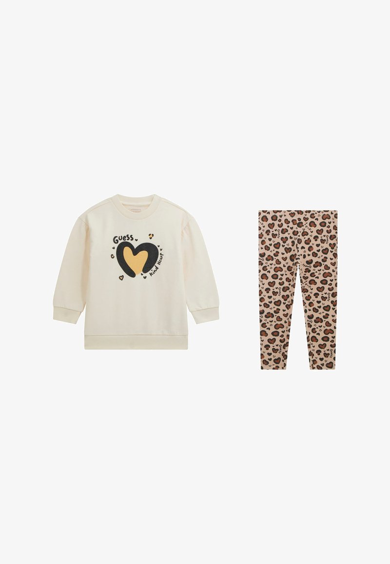 Creme sweatshirt med sort og gul hjertegrafik samt teksten "Guess Kind Heart", parret med beige leopardmønstrede leggings.