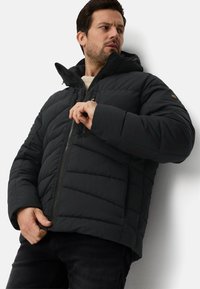 Czarna puchowa kurtka z pikowanym wzorem, kapturem, przednim zamkiem błyskawicznym i bocznymi kieszeniami. Materiał wydaje się gładki i ocieplony dla zapewnienia ciepła.