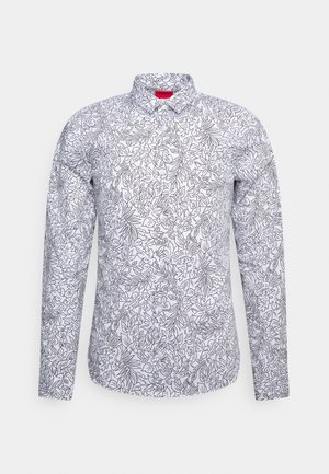 Chemise blanche à manches longues boutonnée avec un motif floral et feuilles en contour noir, col standard et étiquette de marque rouge à l'intérieur de l'encolure.