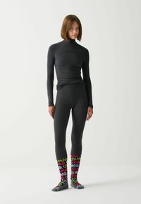 Fekete, hosszú ujjú felső magas nyakkal és fitted leggings. Színes mintás zoknik "Colmar" felirattal rózsaszín, zöld és kék árnyalatokkal.