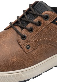 Zapato de cuero marrón texturizado con lengüeta de malla negra, ojales de metal, cordones planos negros y una media suela blanca que presenta una suela de goma con diseño de goma.