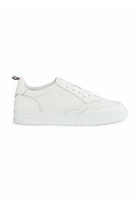 Witte leren sneaker met geperforeerde neus, platte veters en een gestructureerde rubberen zool. Bevat een kleine rode en blauwe accent op de hak.