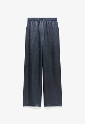 Wide-leg pants made of textured, shiny black fabric. Features an elastic waistband with a drawstring and a relaxed fit.