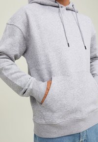 Gray hoodie made of soft fabric, featuring a front pocket, drawstrings, and ribbed cuffs. Simple, relaxed design with a classic fit.