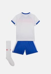 Maillot de sport blanc avec des accents bleus, associé à un short bleu. Comprend une chaussette blanche avec du texte rouge et un logo. Tissu doux et respirant.